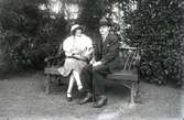 En man och en kvinna sitter på en parksoffa.