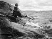 Ester Ellqvist-Bauer sitter på en klippa vid havet.