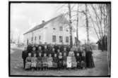 Knarsta skolan, 32 skolbarn med lärare Hilda Lindh.
En och en halvvånings skolbyggnad i bakgrunden.