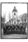 Rinkaby kyrka i bakgrunden.
Konfirmander, 14 ungdomar och prästen
Byggnader.