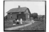 En och en halvvånings bostadshus och ekonomibyggnader.
Tre kvinnor och en man.
Fru Elsa Roth