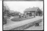 Södergården, två envånings bostadshus med inredd vind och verandor med snickarglädje. Sju personer framför huset.
Adolf Gustafsson