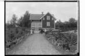 Envånings vinkelbyggt bostadshus med inredd vind, glasad veranda.Tre personer framför huset.Karl Johansson