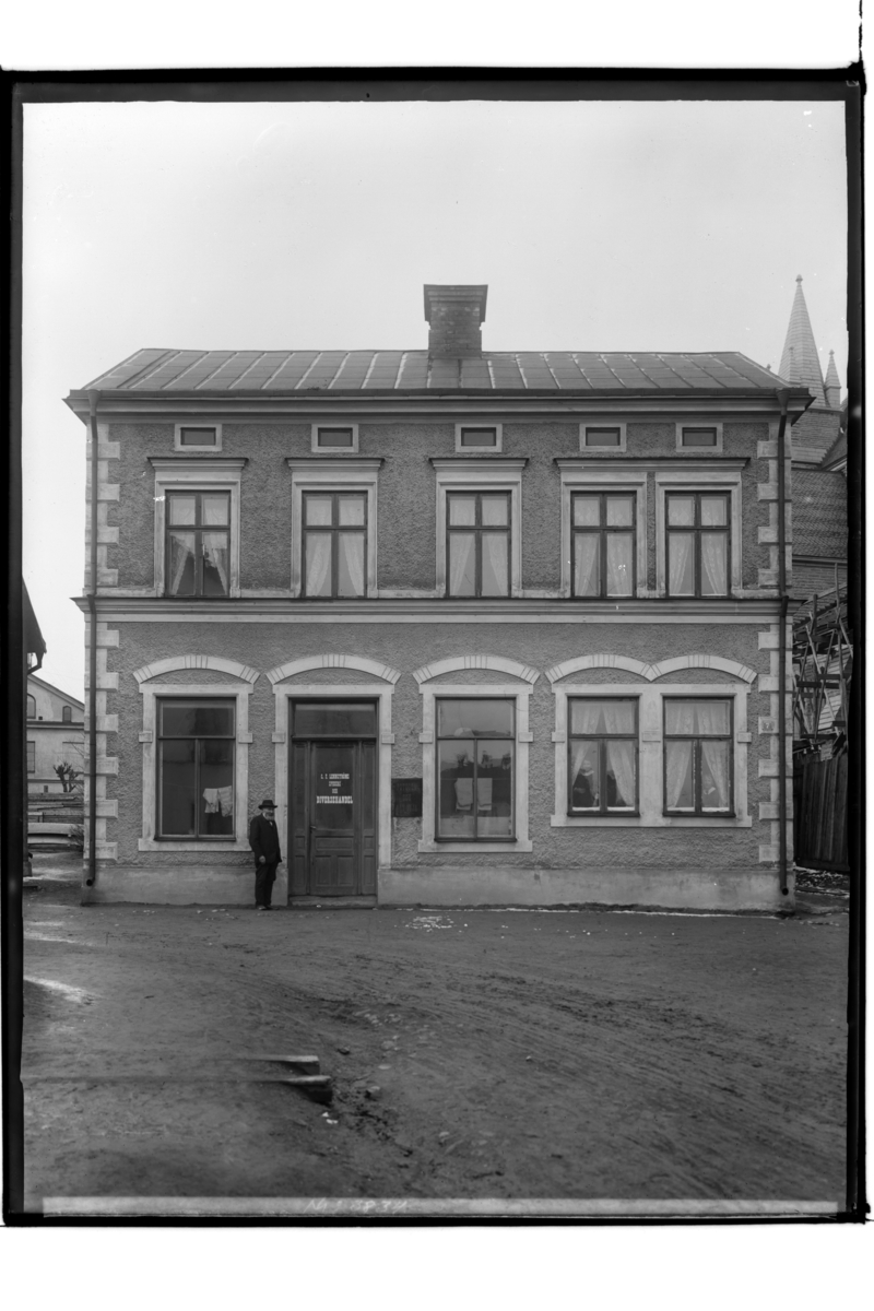 Samuel Lindskog, Two-storey residential building with business in the ground plane. A man on the street. C.F. Lennström