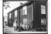 Tvåvånings bostadshus, fem vuxna och tre barn framför huset.
Kronokamrer Inge Sahlin, Örebro.