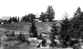 Skommarhyttans hyttruin i förgrunden. Huset på kullen hade Gammelstilla Bruk ställt till förfogande som skolhus innan skolan i Östansjö byggdes på 1880-talet