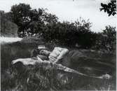 En kvinna sover på en filt på gräsmatta