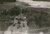 Flygfoto över en herrgård med flygelbyggnad och park.