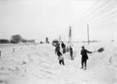 Gatubilder. Snövintern 1929. En mängd karlar skottar snö på en väg.