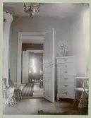 Interiör i Sven Sundbergs hem. Dörr, byrå, barnvagn och matta syns i bild.