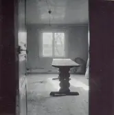 Ett bord och ljus som kommer ifrån ett fönster i en rum i Mjödehult.