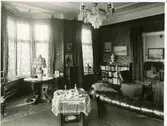 Salong på Bergagården  med fåtölj, soffa, bord, bokhylla och kristallkrona.