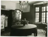 Borgerlig salong med burspråk bord och skåp.