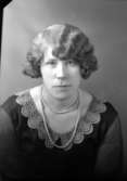 Ateljébild på en kvinna i klänning, spetskrage och pärlhalsband. Enligt Walter Olsons journal är bilden beställd av Anna-Lisa Olaisson.