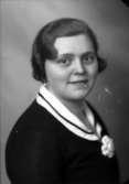 Ateljébild på en kvinna i brosch och klänning. Enligt Walter Olsons journal är bilden beställd av fröken Greta Nilsson.