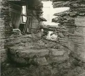 Interiör från ett fallfärdigt hus med eldstad.