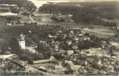 Överblick på samhället med kyrkan och grusvägen och bostadshus.