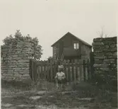 En pojke framför en grind till en gård i Segerstad.