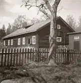 En ladugård med timmervägg och ett staket.