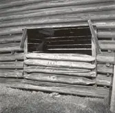 En dörröppning som förseglas med liggande rundtimmer i spår på en ängslada i Skäfshult.