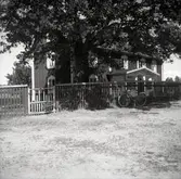 Ett bostadshus med staket, grind och cykel.