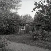 Ett äldre par framför en mindre stuga i Gunnabo