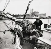 Okänd person ombord på okänt fartyg. I bakgrunden ses Skeppsbron och Ångkvarnen.