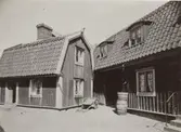 Bostadshus med mansardtak varav den ena har takkupor. Kvarteret Alen 14 i Gamla staden. Västerlånggatan 7, från Molinsgatan. Året är 1908.