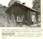 Knuttimrad stuga bakom mangårdsbyggnaden. Den är klädd med panel av stående bräder som skissen visar. Taket är av enkupigt tegel, och stugan är rödmålad
med vita dörr- och fönsterfoder. Observera vindskivorna.