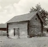 Bod med dubbelknut. Enrummig i två våningar. Övervåningens stockar synliga på baksidan. Endast tomtstenar.