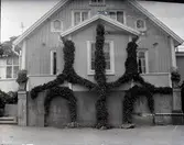 Östra gaveln i Widebergs trädgård.

John Wideberg blev tidigt intresserad av
trädgårdsanläggningar. Han hade sannolikt hämtat
inspiration på resor han gjort till Stockholmsutställningen
1897 och till Göteborg 1923. Han blev också vän med
stadsträdgårdsmästaren Haglund i Kalmar.
John hade palmer i potatiskällaren under huset och påfåglar,
ekorrar och pärlhöns som övervintrade i hönshuset. En
papegoja och en sköldpadda fick tillbringa vintrarna inne i
köket. Runt trädgården planterade han skyddande häckar.
Arbetet påbörjades redan när han var 18 år med att han
hämtade åtta granar i skogen, och planterade dem i en
ring mitt i trädgården. Dessa finns kvar än idag. I slutet
av 1930-talet arrenderades jordbruket ut och John kunde
ägna sig på heltid åt trädgården, som blev alltmer av ett
besöksmål. John började ta inträde, 25 öre.
John utvecklade också sin hobby som tavelmålare och som
fotograf. Han tog med sin lådkamera under årens lopp
hundratals vackra bilder från trädgården, liksom på vyer,
hus och människor i takten. Ca 500 av dessa bilder finns
bevarade som glasplåtar, skänkta till Kalmar läns museum.