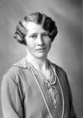 Ateljébild på en kvinna i halsband och klänning. Enligt Walter Olsons journal är bilden beställd av Berta Jakobsson ifrån Kalkstad.