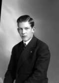 Ateljébild på en man i skjorta, kavaj och slips. Enligt Walter Olsons journal är bilden beställd av Magne Brynjer.
