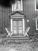 Ytterdörr med vacker dörromfattning och soffor på trappan.