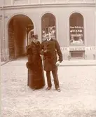 En man och en kvinna framför en butiksbyggnad. Text på skyltfönstret: 