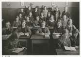 Undervisning i Nisbethska skolan, 1923. Flickor som sitter vid skolbänkar i en skolsal. Några står upp längre bak.
