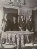 Fyra herrar, stående vid ett bord.