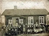 Flohultsläraren K.M. Karlén framför Falla skola omkring år 1900.