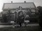 Kvinna och två barn framför ett bostadshus i Widebergs trädgård.