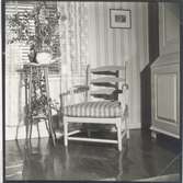 Interiörbild med karmstol och krukväxt på piedestal. Beställd av tidningen Lanthemmet.