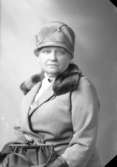 Ateljébild på en kvinna i hatt, handväska och kappa. Enligt Walter Olsons journal är bilden beställd av fru Cohrs.