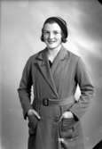 Ateljébild på en kvinna i kappa och mössa. Enligt Walter Olsons journal är bilden beställd av Ruth Andersson.