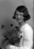 Ateljébild på en kvinna som håller i en blombukett. Enligt Walter Olsons journal är bilden beställd av Maj Johansson.