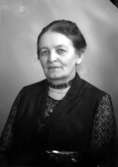 Ateljébild på en kvinna i håruppsättning och halsband. Enligt Walter Olsons journal är bilden beställd av fru kyrkoherde I Hansson.