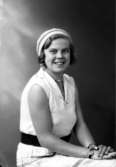 Ateljébild på en kvinna i halsband och klänning. Enligt Walter Olsons journal är bilden beställd av Inga Lindén.