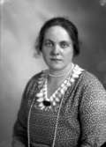 Ateljébild på en kvinna i halsband och brosch. Enligt Walter Olsons journal är bilden beställd av fru Gottfrid Johansson.