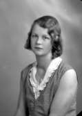 Ateljébild på en kvinna i klänning och medaljong. Enligt Walter Olsons journal är bilden beställd av Ragnhild Jakobsson.