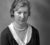 Ateljébild på en kvinna i halsband och spetskrage. Enligt Walter Olsons journal är bilden beställd av Anna Karlsson.