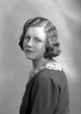 Ateljébild på en kvinnna i halsband och ondulering. Enligt Walter Olsons journal är bilden beställd av Astrid Johansson.