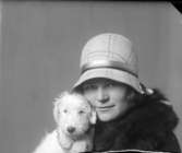 En kvinna i hatt och päls med en hund med koppling till Hirschs Pianomagasin.